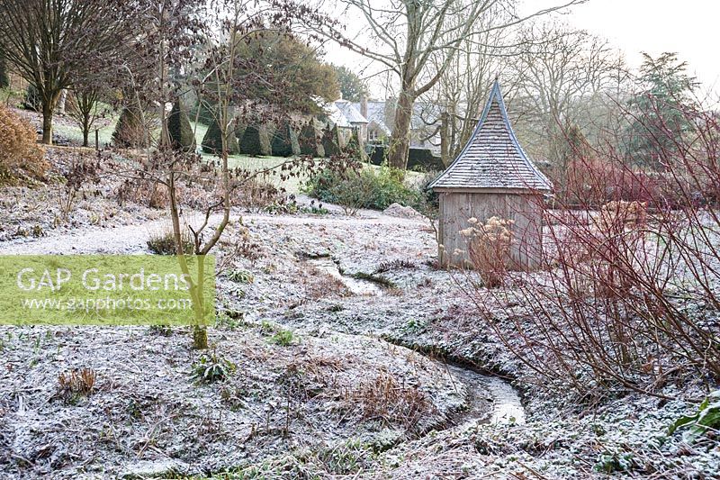 Dormant bog garden with an icing of snow around a wooden summerhouse.