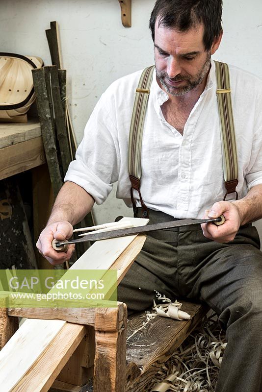 Charlie Groves making a traditional Sussex trug. Astride an old shavehorse, using a drawknife to shave willow boards thinner at either end, so they are flexible enough to press into the frame.