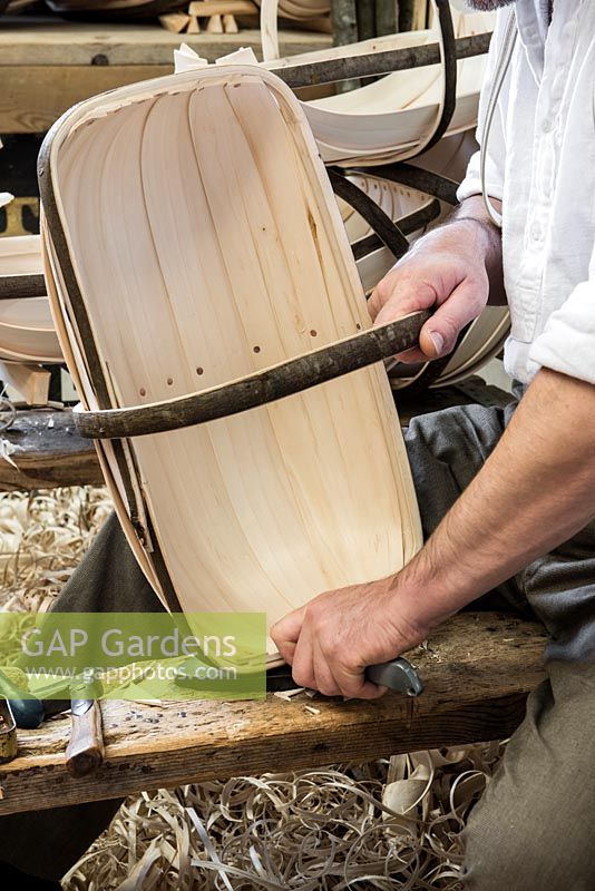 Charlie Groves making a traditional Sussex trug. Using a knife to cut off the excess willow board projecting above the trug rim.