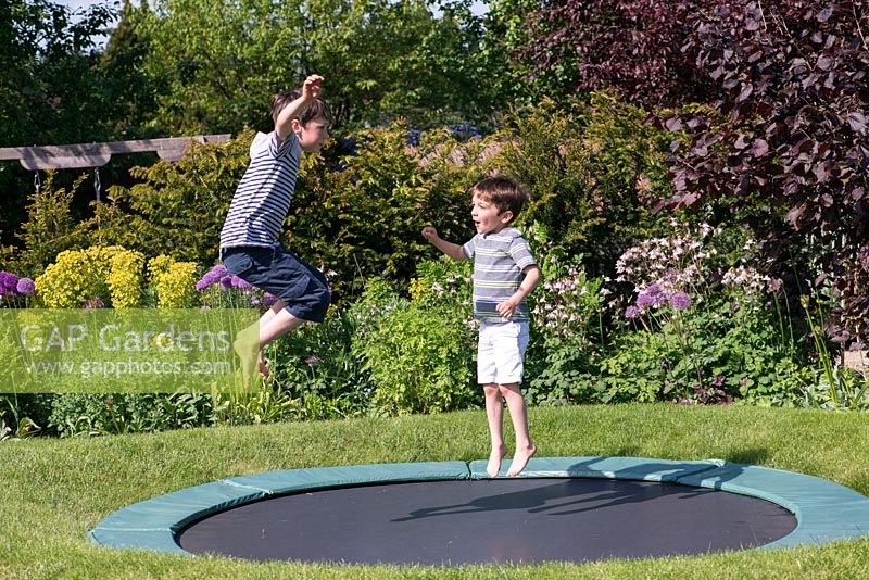 Oscar, 9, and 7-year-old Archie on the trampoline, set into the lawn.