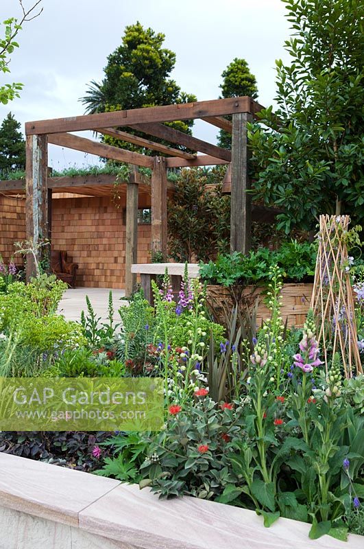 Raised garden bed looking towards recycled timber pergola, cedar shingle clad walled dining area.