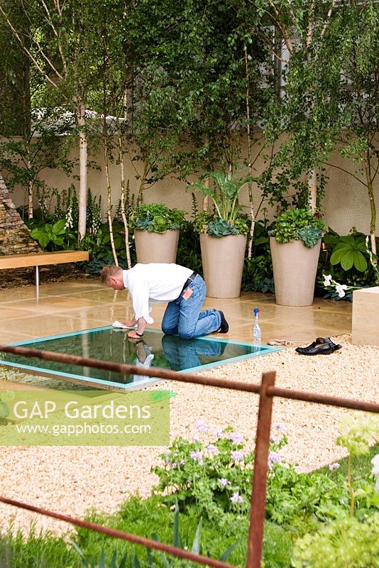 Man wiping away muddy footprints. The Mencap and Cater Allen Bank Garden, Seeing the Whole Picture, Design Ruth Marshall, Chelsea Flower Show 2006