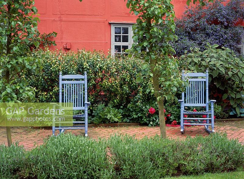 Two pale blue wooden rocking chairs behind a lavender border