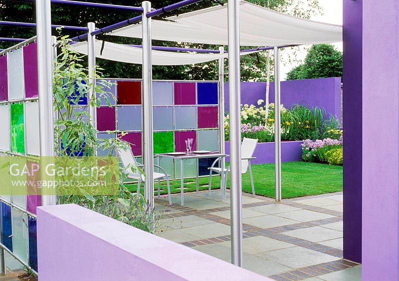 View to patio with metal furniture, perspex screen creates garden room. Design: Jane Mooney -  a versatile garden for modern living. HCFS 2002