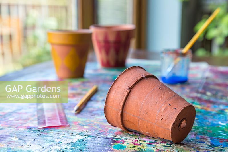 Materials required are a ruler, pencil, terracotta pots, paint brush and paint