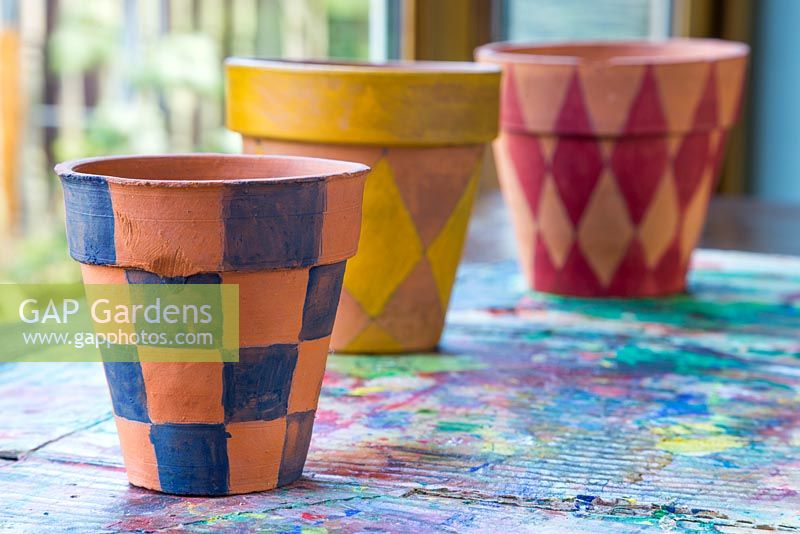 A variety of terracotta pots painted in different colours bearing a Tartan pattern