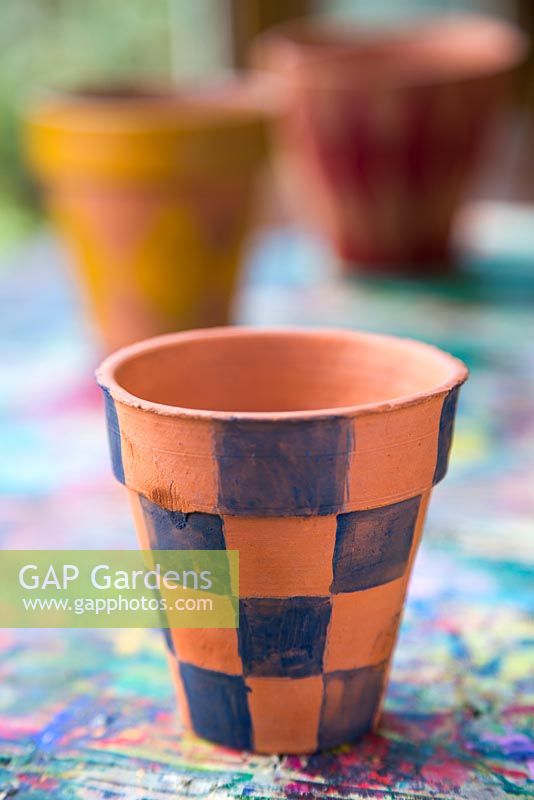 A variety of terracotta pots painted in different colours bearing a Tartan pattern