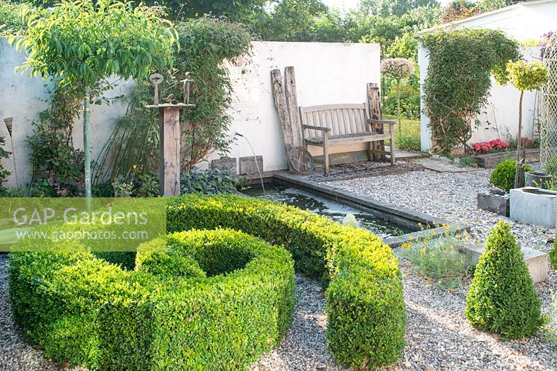 Gravelled courtyard garden with box topiary spiral and bronze sculptures by Christopher Marvell.