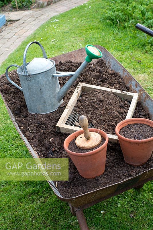Using garden compost for seed sowing - wheel barrow with well rotted garden compost, home made sieve, terracotta pots and traditional watering can.