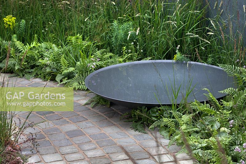 Crescent shaped cobbled path with steel water bowl in'A Quiet Corner' at RHS Tatton Flower Show 2015