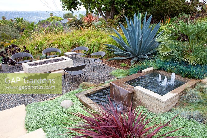 Outside seating area with gas fire pit and concrete contemporary water feature. Debora Carl's garden, Encinitas, California, USA. August.