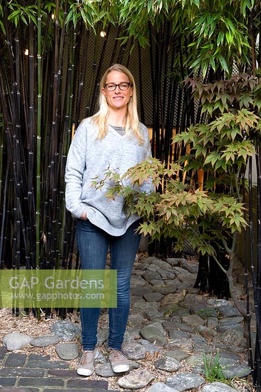 Portrait of the garden owner standing in a grove of black bamboo.