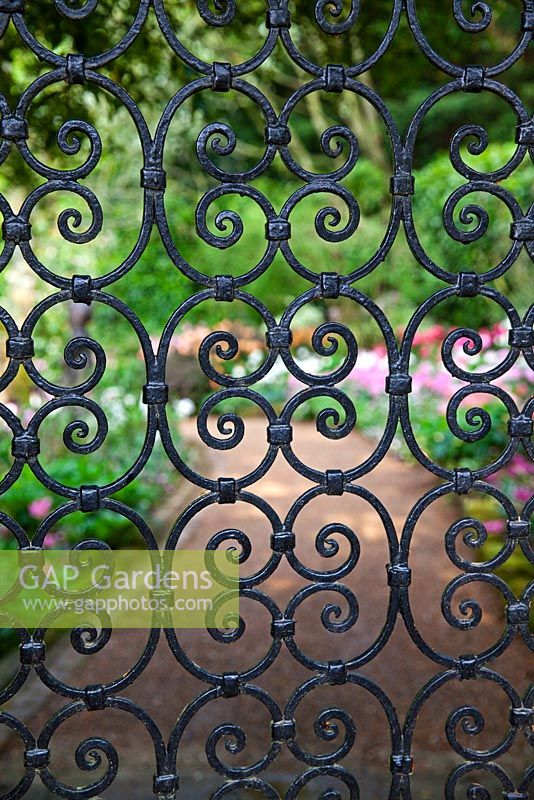 View through wrought iron gate leading to garden - Pashley Manor Gardens, Kent, UK