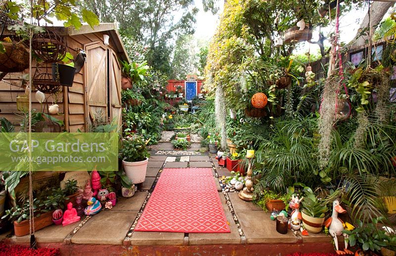 Wide view of inner city garden with begonias, ferns and palms features colourful eclectic retro pieces sourced from local markets. 