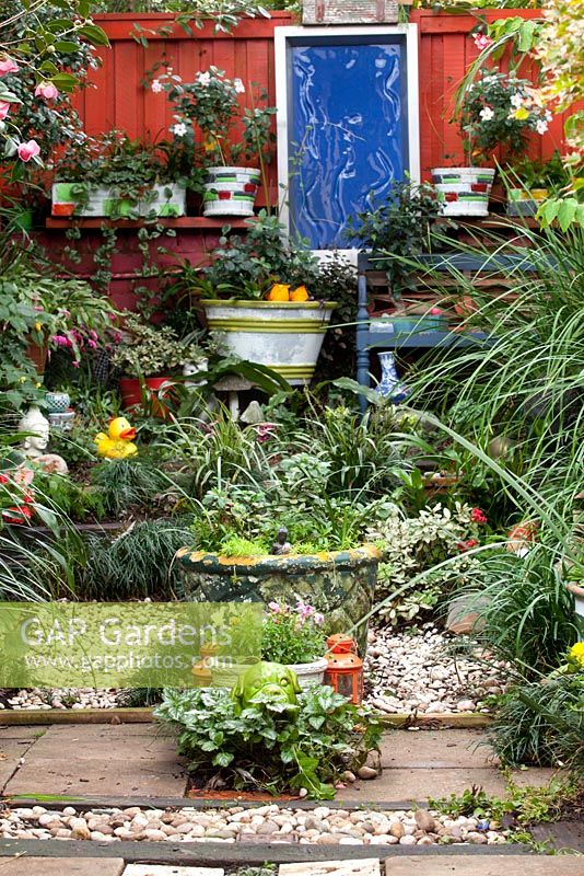 A collection of retro cement pots, quirky garden ornaments and a blue framed garden decoration focal point.