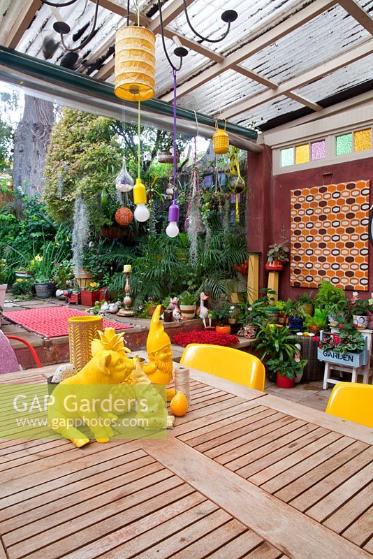 Inner city garden with begonias and spathiphyllums features colourful eclectic retro pieces sourced from local markets, including a timber dining setting with assorted yellow objects