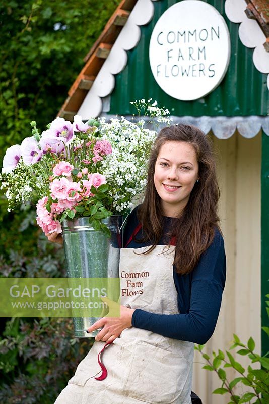 Florist Emily Morriss holding a vase of flowers in the garden. Common Farm Flowers, Somerset 