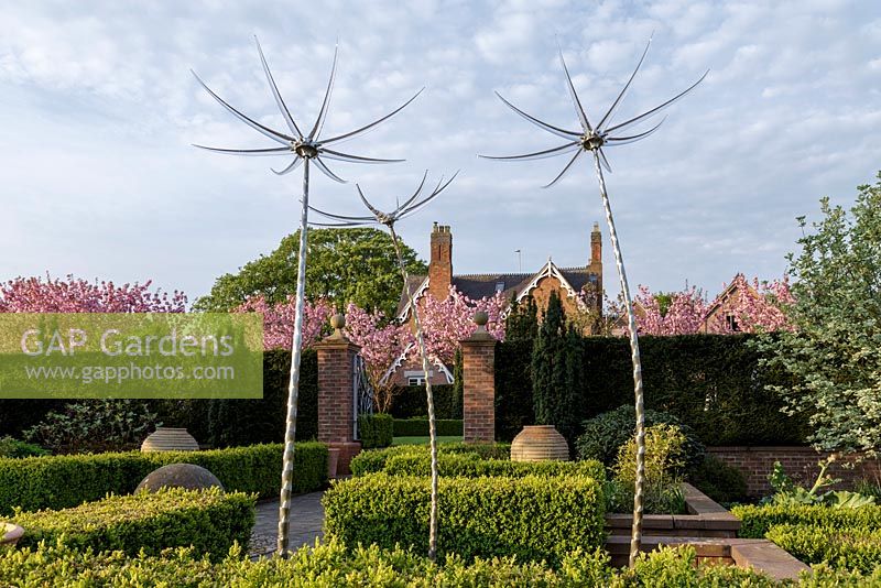 Mitton Manor Garden in spring, Staffordshire. Formal parterre style garden with Neil Wilkin glass sculptures rising from pond
