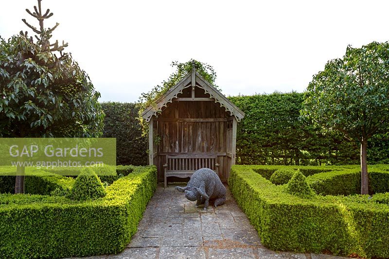 Mitton Manor Garden in spring, Staffordshire. Parterre garden with chicken wire sculpture of pig