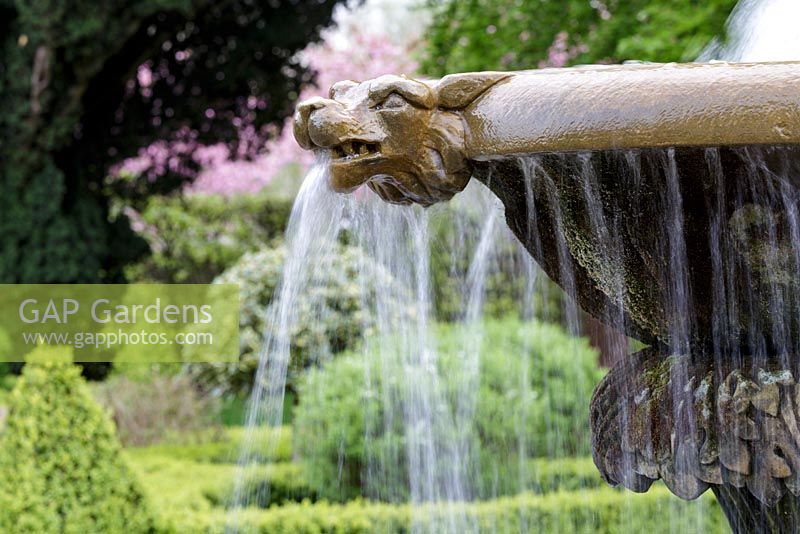 Mitton Manor Garden in spring, Staffordshire. Splashing water feature in formal garden