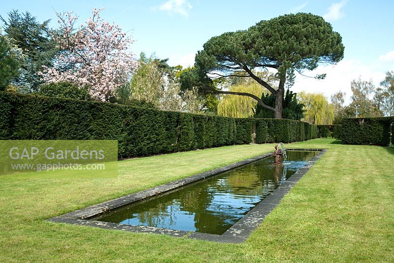 Long narrow pond with sculptured water fountain - Dunsborough Park Gardens, Ripley, Surrey
