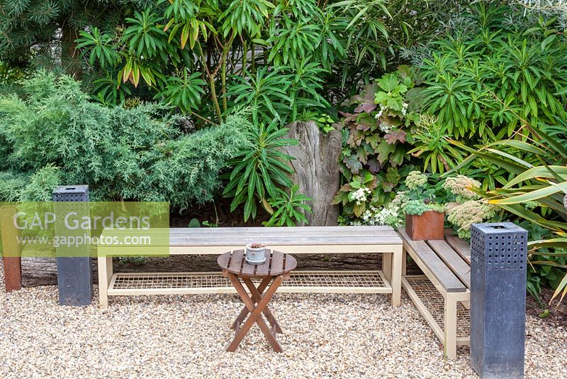 One of several benches in the garden, complete with tall metal candle-holders for warm summer evenings. Planting includes juniper, Euphorbia mellifera, the oak-leaf hydrangea - Hydrangea quercifolia, Sedums and sea buckthorn - Hippophae rhamnoides.