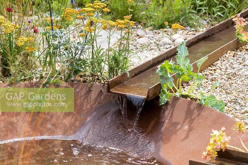 Feel-Good Front Gardens, corten steel rill water feature running into large bowl, with gravel and  naturalistic drought-tolerant planting, including sea cabbage - Crambe maritima, achillea and eryngium. RHS Hampton Court Flower Show in 2016