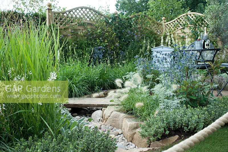 'The Drought Garden', The garden's central feature is a waterless river bed of pebbles, traversed by a yorkstone 'plank' and edged with irregular shaped blocks of purbeck stone. Plants include Verbena bonariensis, Verbascum 'Kynaston', Eryngium 'Jos Eiking', Pennisetum villosum and alopecuroides 'Hameln', Stipa gigantea, Gaura lindheimeri 'Whirling Butterflies', artemisia, stachys and hebe.   Best City Garden: Hampton Court Flower Show, July 2016.
