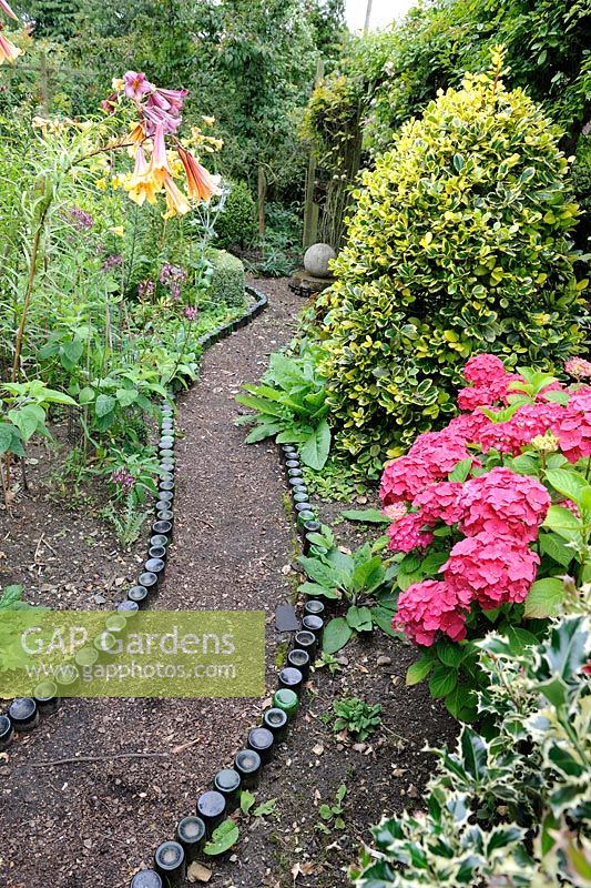 Recycled bottle lined garden path with Hydrangeas and Lillies UK, July