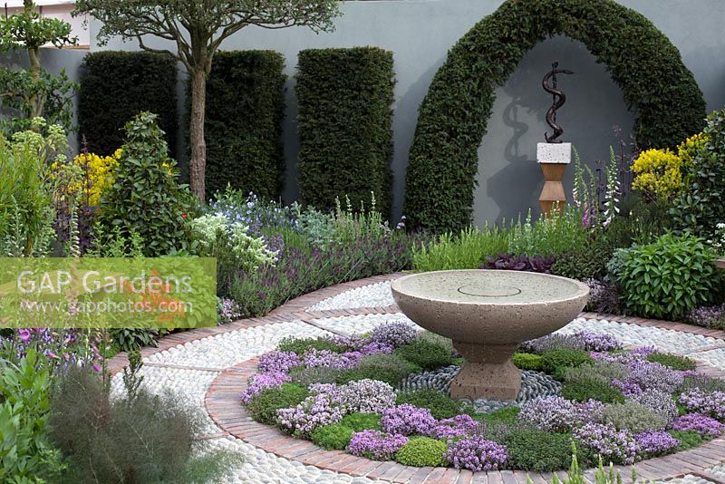 The St John's Hospice - A Modern Apothecary , inspired by the healing power of plants, calming stone water feature in the centre of a spiral cobbled path, bordered by herbs such as fennel, bay, and lavender. RHS Chelsea Flower Show, 2016