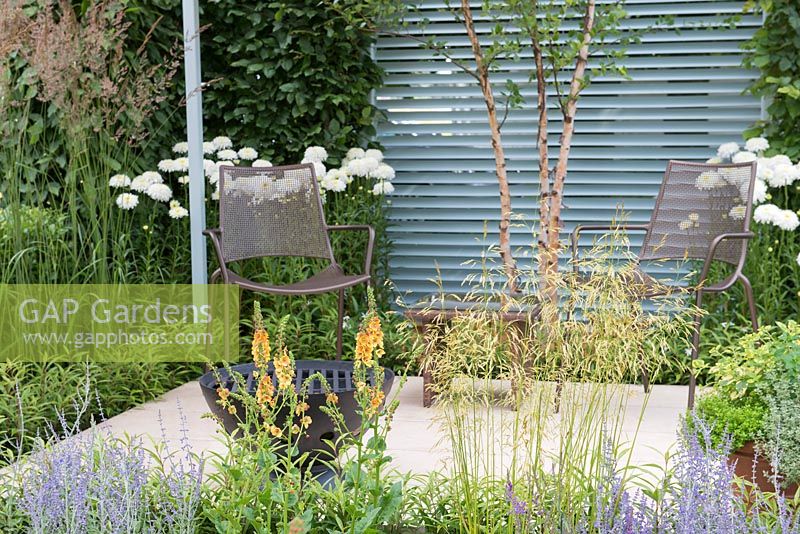 Seating area with firebowl, plants include Verbascum 'Clementine', Perovskia 'Lacey Blue' and Deschampsia cespitosa 'Goldtau' - Final5: Retreat Garden, RHS Hampton Court Palace Flower Show 2016
