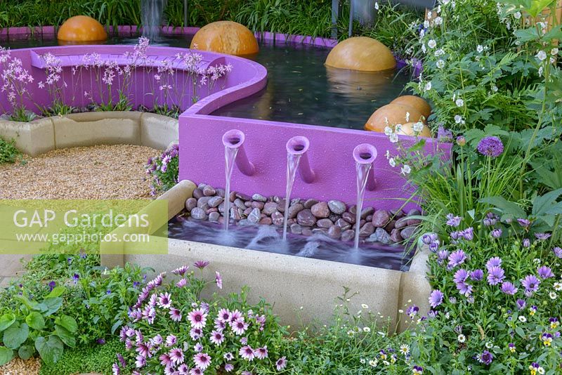 Water cascades from violet pool in Papworth Trust - Together We Can with acoustic effects generated by water merimba. The RHS Chelsea Flower Show 2016. Designer: Peter Eustance MSGD, Sponsor: Papworth Trust. SILVER GILT