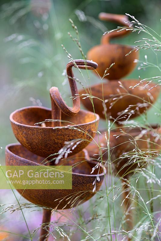Rusted sculptural bird feeders in the RHS Greening Grey Britain for Health, Happiness and Horticulture Garden. RHS Chelsea Flower Show 2016 - Designer: Annie-Marie Powell