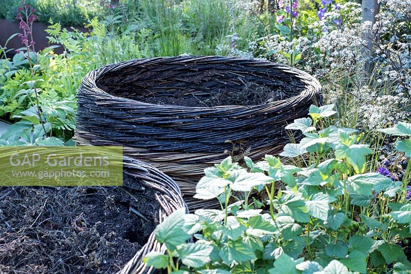 RHS Greening Grey Britian - Willow Compost Bins surrrounded by grasses and Anthriscus sylvestris 'Ravenswing'. RHS Chelsea Flower Show 2016, Designer: Ann-Marie Powell