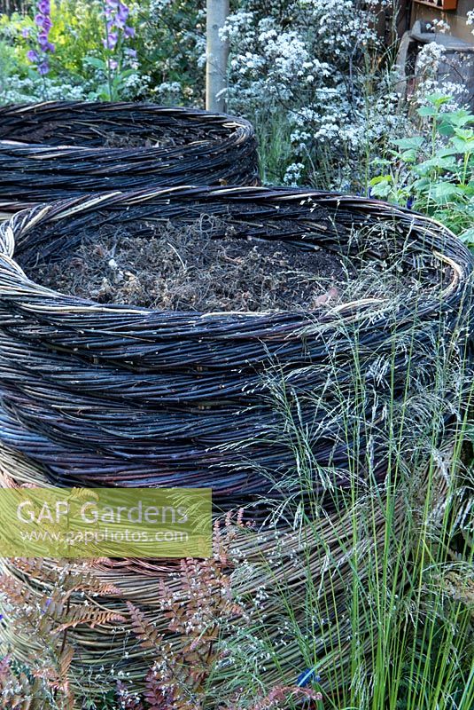 RHS Greening Grey Britian - Willow Compost Bins surrrounded by grasses and Anthriscus sylvestris 'Ravenswing'. RHS Chelsea Flower Show 2016, Designer: Ann-Marie Powell