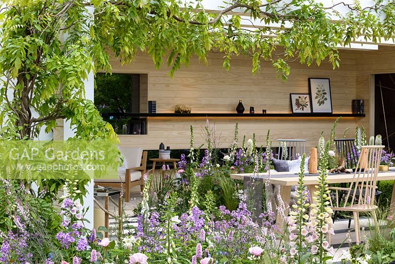An outside-room in The LG Smart Garden, a Scandinavian lifestyle garden inspired by moden technology and softened by delicate pstel planting such as Digitalis 'Glory of Roundway' and Hesperis matronalis and framed by Wisteria 'Schowa Beni'. The RHS Chelsea Flower Show 2016 - Designer:  Hay Joung Hwang - Sponsor: LG Electronics - SILVER-GILT
