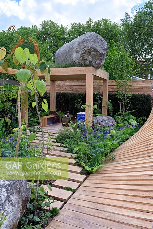 The Garden Of Potential. Sawn timber steps leading to raised Patio. Curving timber wall RHS Chelsea Flower Show 2016. Designer: Propagating Dan, Sponsors: Greenwood Forest Park