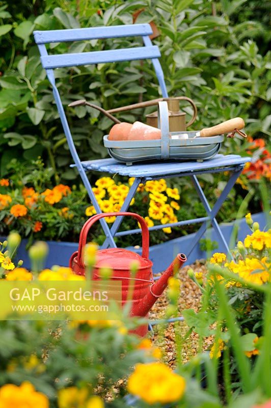 Summer raised bed potager garden with watering can and trug full of garden items, Norfolk, UK, July