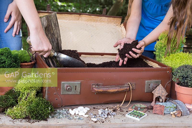 Fill the suitcase three quarters full with compost