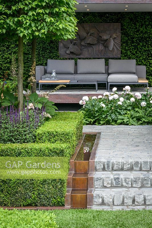 Husqvarna Garden, the seating area with copper water rill and planting including  white Paeony 'Mother's Choice', espaliered Carpinus betulus, Buxus sempervirens topiary, Taxus bacatta hedge. The RHS Chelsea Flower Show 2016 