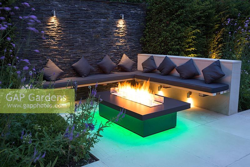 Secluded seating area with a dry stone slate wall and propane fire pit emitting green light