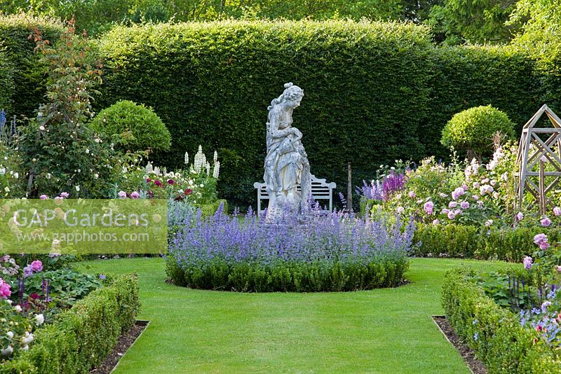 Formal Rose garden with a stone statue underplanted with a circle of Box hedging and flowering Nepeta 'Six Hills Giant', with Roses 'Charles de Mills', 'Mary Rose', 'Munstead Wood', 'The Pilgrim', 'Fantin Latour'