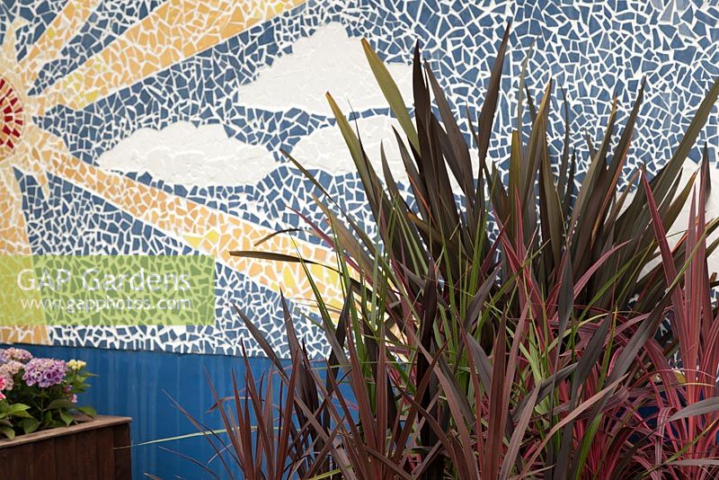 A sun, sky and cloud mosaic with a group of green and red leaved cordylines in front. From here to there, RHS Tatton Flower Show 2011, Cheshire