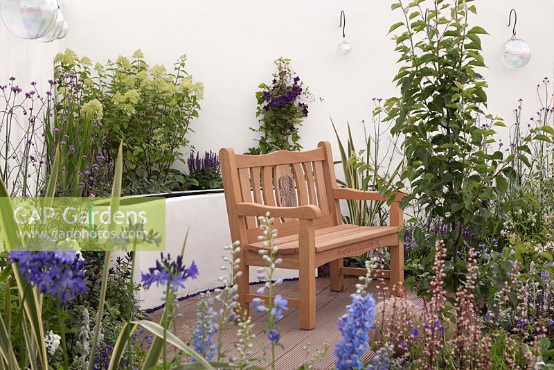 A patio with white walls, raised beds with blue, purple and lime green perennials and a natural wooden bench. A breath of fresh air, RHS Tatton Flower Show 2011, Cheshire