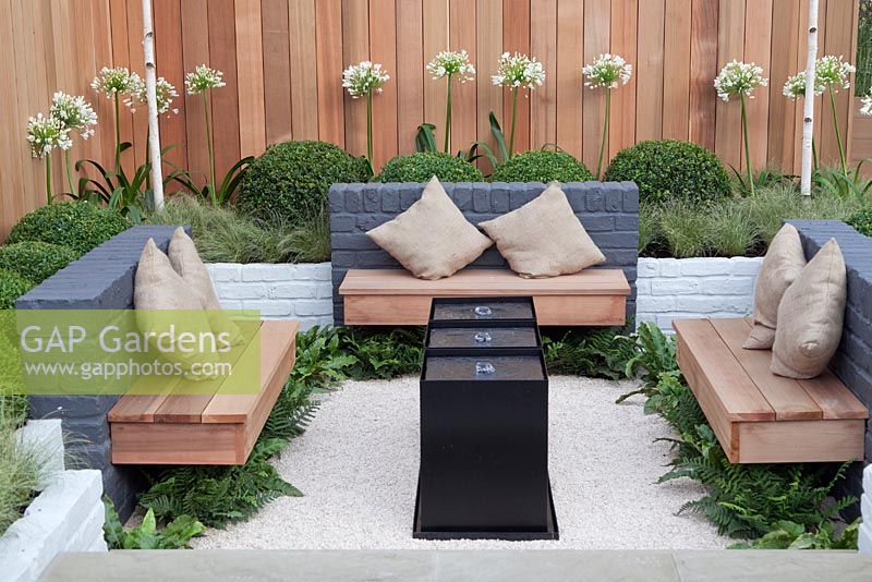 A grey, black and white minimalist sunken seating area with sustainable timber cladding fences and benches. Minimal Impact Garden, RHS Tatton Flower Show 2011, Cheshire