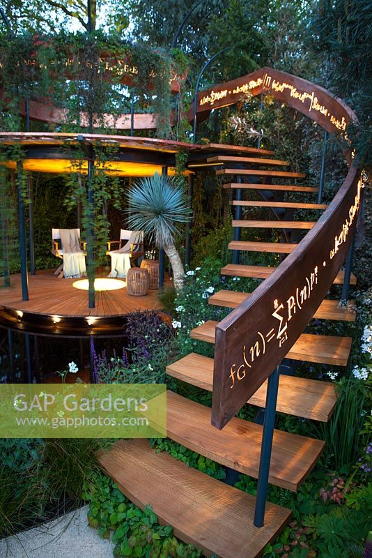 Belvedere in the Winton Beauty of Mathematics Garden lit at night, RHS Chelsea Flower Show 2016. Illuminated mathematical symbols cut into band of copper to form bannister for staircase