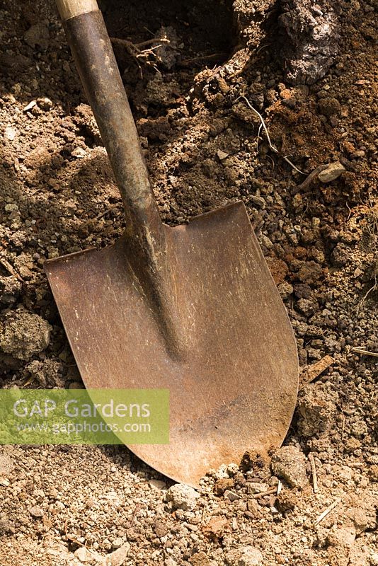 Close-up of old rusted metal digging shovel in dirt pit