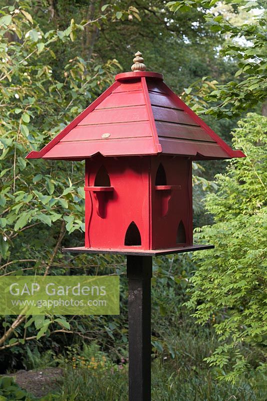 Red painted wooden bird house in woodland - June, Clyne Gardens, Swansea, Wales
