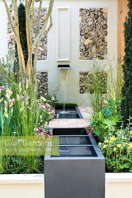 A Suffolk Retreat. Water trough flanked by perennials, Iris 'Jane Philips' and yew. Sponsor: The Pro Corda Trust. Designer: Freddy Whyte. RHS Chelsea Flower Show 2016