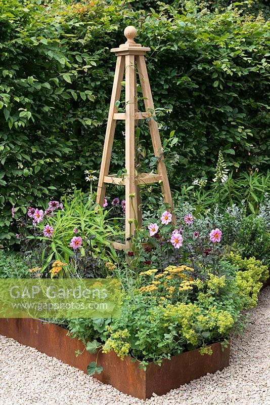 An Arts and Crafts inspired garden with hornbeam hedge, raised corten steel border and hand crafted obelisk. A Summer Retreat designed by Laura Arison and Amanda Waring. RHS Hampton Court Flower Show 2016